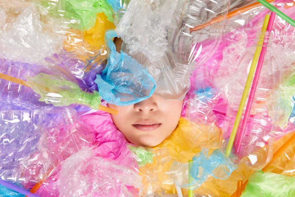 Micro-Contaminación: Mujer irreconocible totalmente cubierta con basura plástica, solo se le ve la boca y la nariz, lucha contra ella.
